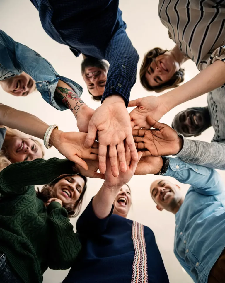 A bottom up shot of a group of people with their hands in the centre of the frame.